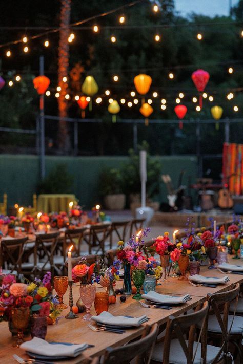 This whimsical + eclectic party was hosted at a sprawling Hollywood Hills Estate. The tennis court was transformed with a variety of lounges offering a travelled aesthetic. Colorful Vietnamese silk lanterns hung over the al fresco dinner tables and floating pool lanterns added a magical touch! Guests enjoyed an Aperol spritz bar and a Mediterranean grazing table in a beautiful garden. Flowers in pottery + brass. Mismatched colored goblets. Photo: Erin Marton, Planning: Art & Soul Events Mexican Dinner Party Aesthetic, Backyard Eclectic Wedding, Mexican Vietnamese Wedding, Pride Dinner Party, Mexican Theme Pool Party, Outdoor Summer Dinner Party Aesthetic, Eclectic Colorful Wedding, Mexican Themed Dinner Party, 40th Dinner Party Ideas