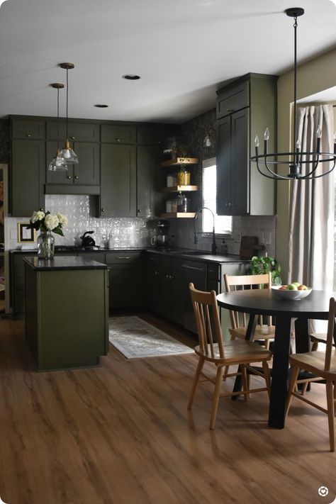 Green kitchen cabinets with light brown LVP flooring. Black chandelier with black soapstone countertops Moody Green Kitchen, Dining Pantry, Lauren Diy, Moody Kitchen, Moody Green, Dark Green Kitchen, Dark Countertops, Black Countertops, Green Kitchen Cabinets