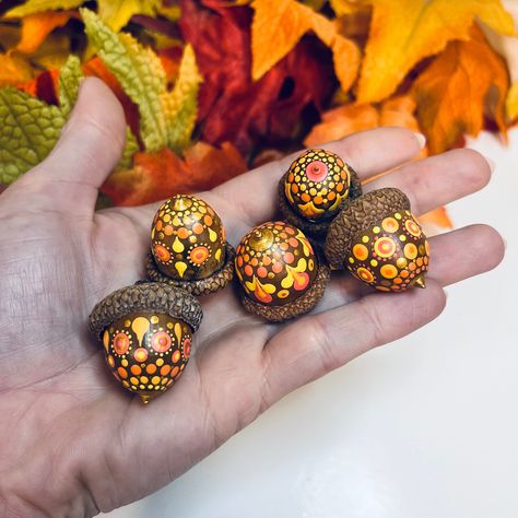 This listing is for a set of five (5) hand painted large (2) and jumbo (3) acorns in yellow, orange, salmon pink and metallic gold. Your set will be chosen at random and will contain one of each pattern pictured.  The acorns were collected in the Outaouais region of Quebec, Canada, dried, washed, baked, painted , and then sealed with satin varnish for protection.  The large acorns measure approximately: . 75 inches wide x 1 inch tall (not including stem) The jumbo acorns measure approximately: Crafts Using Acorns, Acorn Painting Ideas, Paint Acorns Crafts, Acorn Painted Rocks, Painted Acorns Ideas, Dot Art Patterns, Conker Art Autumn Crafts, Acorns Crafts, Painting Acorns