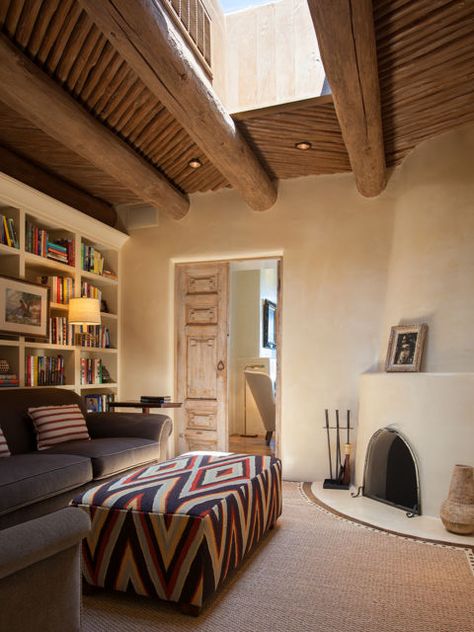 This cozy sitting room off the master suite features classic Southwestern touches, such as a kiva fireplace, hand-plastered walls, and carved wooden doors. A stunning skylight brightens up the space during the day. Modern Adobe House Exterior, Adobe House Exterior, Modern Adobe House, Adobe House Plans, Modern Southwest Style, Santa Fe Decor, Modern Adobe, Santa Fe Style Homes, New Mexico Style