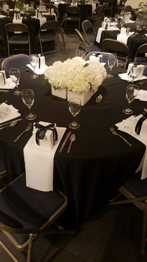 Brunch Table set up for 2018 SHINE!  Look around the picture to see each table showcased many different types of fresh WHITE flowers, grouped in a variety of vases.  The table cloths were black, the linen napkins were draped over the table and held in place by the brunch gift (see pic for detail).  All tables were circular and seated 8 people comfortably.  Thanks Tara for this pic! Black Table White Napkins, Black Tablecloth White Napkins, Black Chair Covers, Brunch Gifts, Black Round Table, Brunch Table Setting, White Chair Covers, 60 Birthday, Black Napkins