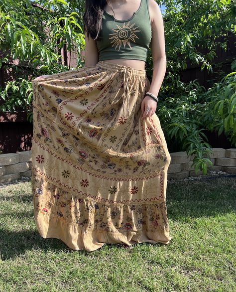 "Introducing our Pari Vintage vibe Light Brown Embroidery Maxi Skirt, perfect for embracing those boho hippie vibes! This stunning skirt features pleated boarder that adds a touch of elegance, while the maxi length offers a chic and comfortable fit. Crafted with fairycore fashion in mind, this skirt is ideal for creating enchanting cottage core looks. Whether you're strolling along sandy shores or exploring hideaways, this skirt will ensure you're dressed to impress. Its flowing silhouette captures the essence of fairycore aesthetics, evoking a sense of whimsy and magic.  Designed for the boho fashionista in you, it is versatile and easy to style. Pair it with a cropped top and woven sandals for a carefree bohemian look, or opt for a lace blouse and floppy hat for a more sophisticated beac Modern Outfit Aesthetic, Earthy Aesthetic Clothes, Cottagecore Boho Outfits, Folky Outfit, Vintage Long Skirt, Whimsical Skirt, Bohemian Clothing, Bohomeian Style Outfits, Cottage Core Maxi Skirt