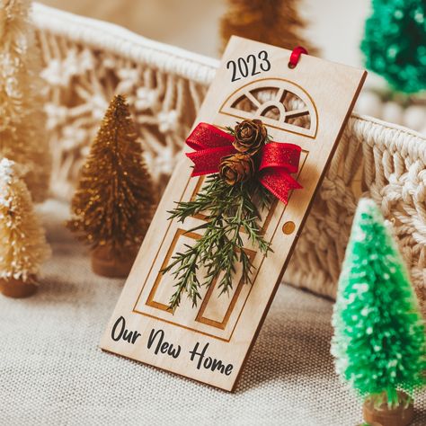 "Congratulate the new homeowners and thank them for their business!  Your thoughtfulness will be a reminder year after year, as they celebrate the holidays in the dream home you helped them find. Embellished with a mini door swag, red sparkly bow, and real pine cones, this laser-cut wood door ornament is personalized with \"2022 Our New Home,\" or another phrase from the drop-down menu. DETAILS - Measurements: 5.5 in x 2.5 in x 1.25 in - Gift wrapping is available in the Options drop-down menu, Real Estate Client Gifts, Glowforge Projects, Door Ornament, Modern Bouquet, Real Estate Closing Gifts, Custom Wood Doors, Neighbor Christmas Gifts, Our First Home, Door Swag