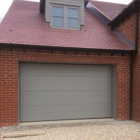 Pair of Novoferm iso 45 Large Rib Sectional Garage Doors in Woodgrain RAL 7030, installed in East Hanney Our second development for this property developer, we installed a pair of Novoferm iso45 Large Rib Sectional Garage Doors in RAL 7030 to match the window frames. Door Specification: iso45 Insulated, Automated Sectional Garage Door by Novoferm Large … Rolling Garage Door, 1930s House Exterior, Roll Up Garage Door, Garage Door Colors, Dormer Bungalow, Cottage Front Doors, Garage Door Windows, Sectional Garage Doors, Property Developer