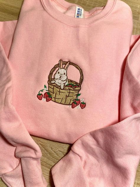 Introducing our Strawberry Basket Bunny Embroidered Sweatshirt 2D Crewneck Sweatshirt, a delightful and charming addition to your wardrobe. Designed for both men and women, this sweatshirt is a perfect blend of comfort, style, and versatility. At first glance, the detailed embroidery of a cute bunny nestled in a basket of fresh strawberries catches your eye. The intricate stitching brings the design to life, adding a touch of playfulness to your outfit. Made with precision and care, this embroid Strawberry Embroidered Sweatshirt, Croquette Outfits, Cute Sweatshirts Outfits, Makeup Embroidery, Crew Neck Embroidery, Sweatshirt Design Ideas, Strawberry Basket, Shirt Outfit Ideas, Comfy Sweatshirts