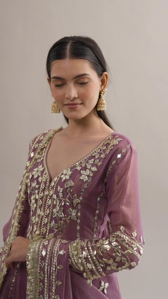 Embrace elegance with our Purple Gotta Patti Dhoti Suit. It features intricate mirror work, beads, gotta patti detailing and tassels. The silk kurta is paired with silk tissue dhoti and a matching floral dupatta. This ensemble exudes sophistication, perfect for wedding wear. Package includes one kurta, dhoti, and dupatta. Pakistani Silk Suit Designs, Kinari Work Suits, Tissue Silk Suit Design, Gotta Patti Kurti Design, Tissue Silk Suit, Pakistani Suits For Wedding, Mirror Work Gharara, Gotta Work Dresses Pakistani, Gotta Patti Suits Pakistani