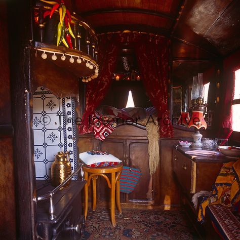 Inside a Romany caravan with a bed area piled with cushions and screened by red curtains. The living area has a blue and white tiled stove and built in cupboard. Romani Caravan Interior, Interior Design Institute, Built In Cupboards, Caravan Interior, Blanket Cover, Red Curtains, Retro Interior, French Interior, Small Space Living