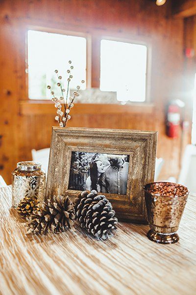 Scattered pinecones, both bare and sprayed with glitter, pair with mercury candles and a wooden picture frames for rustic vibes. Diy Winter Wedding, Modern Wedding Centerpieces, Winter Wedding Table, Winter Wedding Centerpieces, Painted Frames, Winter Party Decorations, Fun Wedding Decor, Elegant Winter Wedding, Winter Centerpieces