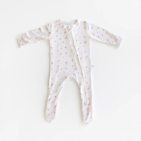 A long-sleeved white baby onesie with a delicate floral pattern, featuring tiny pink flowers, is laid flat on a white background. The onesie has a front zipper and covered feet. Drawn Strawberry, Adorable Style, Sock Booties, Bamboo Pajamas, Sustainable Fabric, Strawberry Print, One Piece Swim, Knit Sweatshirt, Sustainable Fabrics