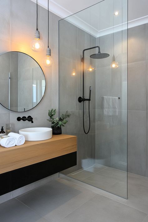 Discover sleek, modern bathroom ideas with this stylish design. Features include a minimalist glass shower, elegant round mirror, and chic black fixtures for a contemporary touch. Elevate your space with these clean lines and neutral tones. #ModernBathroomIdeas #HomeDesign #BathroomInspo Minimalist Bathroom With Bathtub, Neutral Bathroom Black Fixtures, Showers With Black Fixtures, Black White Gray Bathroom Ideas, Darker Bathroom Ideas, Shower Tile Ideas Modern, Organic Modern Bathroom Mood Board, Quick Bathroom Makeover, Gray Small Bathroom Ideas