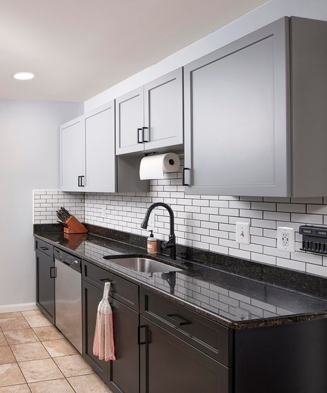 Two-tone gray and black cabinets create visual interest and make a small kitchen seem more spacious. The fog gray wall cabinets and black base cabinets accentuate the existing black granite countertop and white subway tile backsplash. This Two-Tone Kitchen with Fog Gray Wall Cabinets and Black Base Cabinets in Woodbridge, VA was Refaced by Kitchen Saver. See the Full Gallery of Pics on our site at: https://bit.ly/3HxAr3p Black Counter And Black Cabinets, Black Lower Cabinets Grey Upper, White Upper Cabinets Dark Lower Black Countertops, Black And Gray Cabinets Kitchen, Kitchen Tiles With Black Granite, Two Tone Black And Grey Kitchen Cabinets, Subway Tile Kitchen Black Countertop, Black Gray And White Kitchen, Black Kitchen Cabinets With Gray Walls