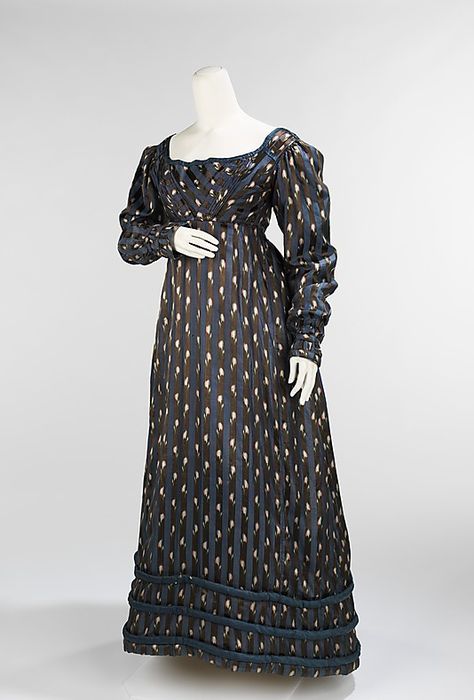 Dinner dress British, silk. 1820. Met museum. Fantastic stripe pattern, used to emphasise the shape on the bodice. Is it poss to be bold and understated at the same time? The bark blue stipe emph the vertical fall of the skirt against the dark ground.The alternating white flower motif breaks this - creating subtle diagonal lines that moves around the skirt. From a distance would this just look dotty, by candle light  I guess the sheen on the fabric would enhance movement making it shimmer. 1820s Dress, 1820s Fashion, Dress Dinner, Regency Era Fashion, 1800s Fashion, Greco Roman, Regency Dress, Regency Fashion, 19th Century Fashion