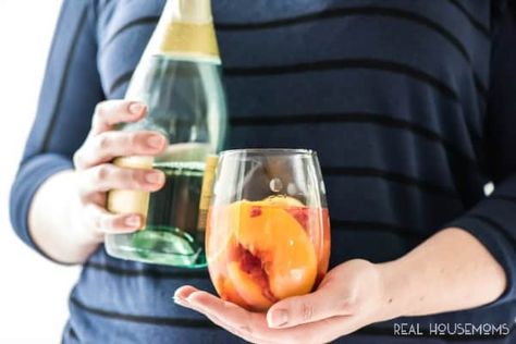 Sparkling White Peach Sangria-Easy Sangria Recipe-Real Housemoms: Sparkling White Peach Sangria is a great brunch or summer cocktail! Making it ahead makes it a great recipe for a party and the taste is fantastic! #champagne #cocktail #peach #peach-schapps #pinot-grigio #raspberry #wine #drinks-recipes #mothers-day-drink #recipes #realhousemoms Girly Cocktails, Wine Slushie Recipe, Party Punches, Party Beverages, White Peach Sangria, Sangria Drink, Easy Sangria Recipes, Peach Wine, Wine Slushie