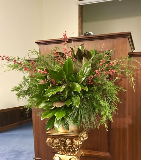 Church flower arrangement. Winter greens, cedar, long needle pine and magnolia leaves with pops of Pyracantha. Winter Church Flower Arrangements, Floral Arrangements For January, January Floral Arrangements For Church, January Flower Arrangements For Church, Winter Flower Arrangements For Church, Church Alter Floral Arrangements, Church Flower Arrangements Altars Ideas, Amaryllis Centerpiece, Christmas Altar