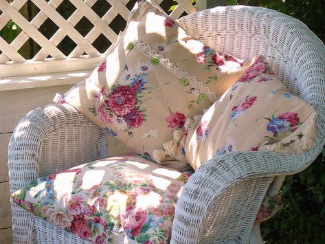 Pretty floral pillows in white wicker chair-(love the way the sunlight casts the shadows on the chair)! Porch Trellis, Wildflower Patch, Porch Pictures, White Wicker Chair, Outdoor Wicker Chairs, Vintage Porch, Wicker Mirror, Linen Cushions, Cottage Rose