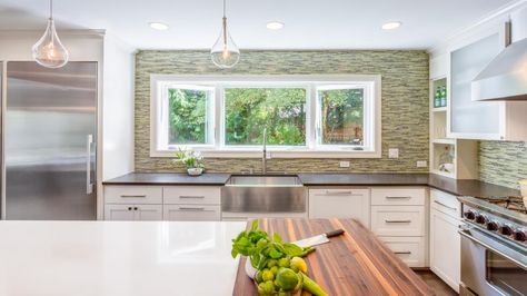 A 9-foot long window was added over the sink in this charming contemporary kitchen, creating lots of natural light in the space. The mood is kept bright and fresh with white cabinetry and a mottled green backsplash. Long Kitchen Window, Travertine Tile Kitchen, Kitchen With Green Backsplash, Windows Above Sink, Kitchen Windows Above Sink, Kitchen Window Over Sink, Window Above Sink, Kitchens Countertops, White Contemporary Kitchen