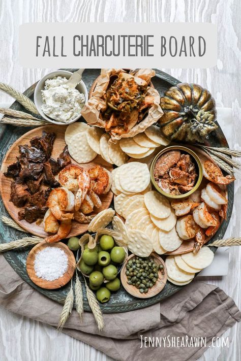 An image for a fall seafood platter with tuna jerky, sauteed shrimp, canned salmon, seachi, olives, capers, crackers and Boursin cheese on a wooden table with a tan napkin. Winter Platter, Seafood Board, Fall Charcuterie Board, Fall Charcuterie, Fall Appetizer, Pool Party Food, Smoked Oysters, Fall Appetizers, Cheese And Crackers