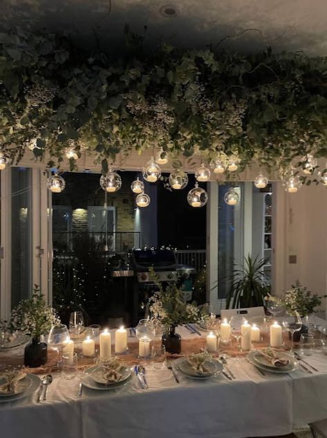 Holiday table with overhead garlands and small lights, candles on table Christmas Table Decorations Diy, Twisted Candles, Table Decoration Ideas, Christmas Table Decoration, Table Garland, Christmas Interiors, Hanging Garland, Beach Christmas, Nordic Christmas