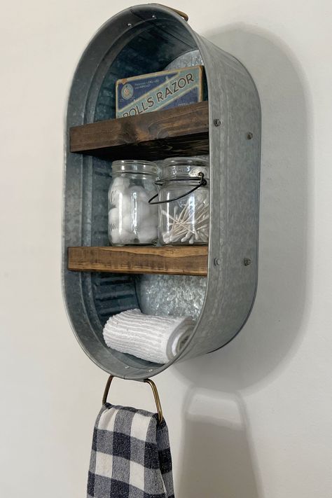 Description:  Add some rustic charm to your home with this Galvanized Metal Wash Tub Wall Shelf.  This Metal rustic shelf is the perfect addition to any room, bathrooms, kitchens, laundry rooms and more. Hang your favorite hand towel from the bottom ring.  Galvanized Metal Tub - Arrives Fully Assembled and Ready to Hang - Hardware Included.    Perfect Size to Hold Small Accessories, i.e. Hand Towels, Soaps, Cotton Swabs, Coffee Mugs,  or Cute Decor. The handle on the bottom of the washtub is per Ny Bathroom, Lighthouse Bathroom, Lodge Bathroom, Farmhouse Bathroom Accessories, Livestock Barn, Rustic Metal Decor, Shelf Vintage, Farmhouse Shelf, Metal Tub