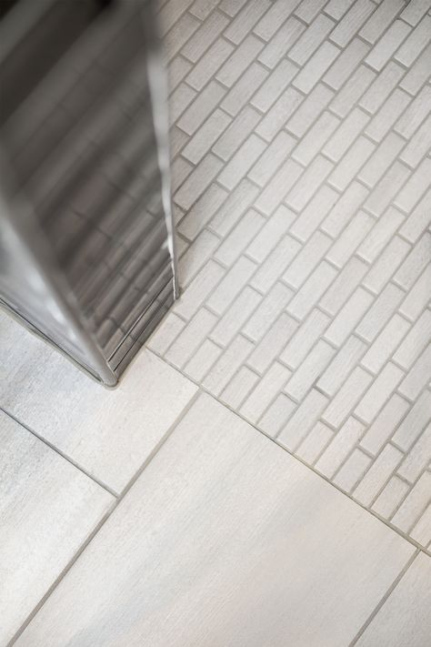 A primary or master bathroom remodeled with a modern/traditional design using shades of grey and off white. Glossy rectangular shower tile set in a herringbone pattern is the statement maker Walk In Shower Floor Transition, Low Threshold Shower Ideas, No Threshold Shower Master Bath, Zero Transition Shower Floor, Tiled Shower Threshold, Threshold Between Tile And Wood Floor, Curbless Shower Pan, Floor Transitions, Floor Transition