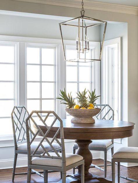 A Darlana Lantern lights a round wood dining table surrounded by dove gray bamboo dining chairs placed in front of windows in a chic breakfast nook. Round Wood Table, Bamboo Dining Chairs, Breakfast Nook Table, Nook Table, Transitional Dining Room, Round Wood Dining Table, Bamboo Chair, Table Makeover, Breakfast Table