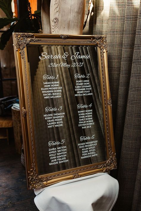 Gold antique frame for mirror with white writing for seating chart Wedding Table Seating Chart Ideas Gold Frames, Scottish Decorating Ideas, Mirror Table Seating Chart, Wedding Mirror Seating Chart, Table Plan Ideas, Venue Aesthetic, Classic Traditional Wedding, Wedding Scottish, Mirror Seating Chart