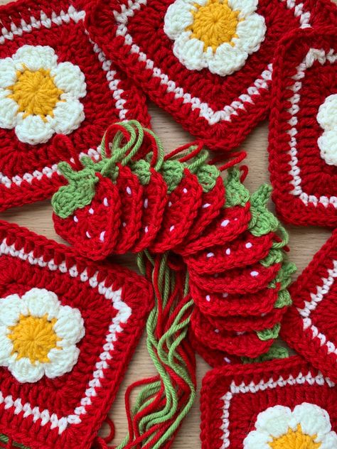 White crochet flower on granny squares and strawberry crochet appliqués laid out in an arc in the middle Strawberry Crochet Blanket Pattern, Cute Granny Squares Crochet, Strawberry Applique Crochet, Strawberry Crochet Granny Square, Strawberry Granny Square Free Pattern, Strawberry Granny Square Pattern, Crochet Strawberry Blanket, Strawberry Crochet Blanket, Fruit Granny Square