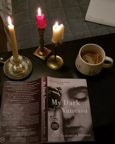 Three candles and a cup of tea sit on a table with a book titled My Dark Vanessa. The book has a black and white cover, a photo of a girl's face with a butterfly. My Dark Vanessa Book Aesthetic, My Dark Vanessa Book Cover, My Dark Vanessa Book, Vanessa Aesthetic, My Dark Vanessa Aesthetic, Vanessa Core, My Dark Vanessa, Rick I Morty, Fairytale Decor