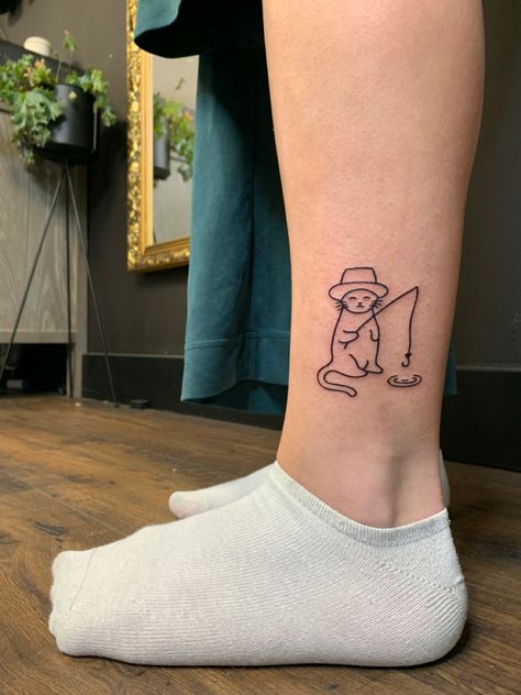 Lower leg tattoo of a cat wearing a hat fishing from a small puddle Minimalist Funny Tattoo, Cat Tattoos Funny, Funny Men Tattoo Ideas, Silly Fine Line Tattoo, Cat Fishing Tattoo, Silly Line Tattoos, Cat Tattoo On Leg, Small Silly Tattoos For Women, Cat Tattoo Patchwork