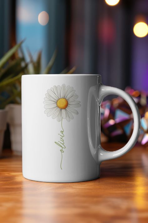 Sip your favourite beverage in style with our Daisy Delight Personalized Mug! Adorned with a charming daisy design, this mug brings a touch of nature's beauty to your everyday routine. Customize it with your name to make it uniquely yours or create a heartfelt gift for someone special.   *Promotional imagery serves solely to showcase the design aesthetic. The item you will receive is a standard 11oz mug.* Customized Mug Gift, Mug Name Designs, Mug Custom Design, Personalised Gifts Mugs, Flower Engraved Mug, Mugs Aesthetic, Mug Designs Flowers, Daisy Mug, White Coffee Cups