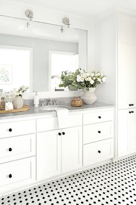 Bright and airy white bathroom boasting vintage black and white floor tiles complementing white cabinets with oil rubbed bronze knobs and a gray marble countertop. Warm Modern Kitchen Design, Black And White Floor Tiles, Blue Tile Backsplash Kitchen, White Floor Tiles, Classic Bathroom Tile, Blue Kitchen Tiles, Bria Hammel Interiors, Black And White Floor, Bria Hammel