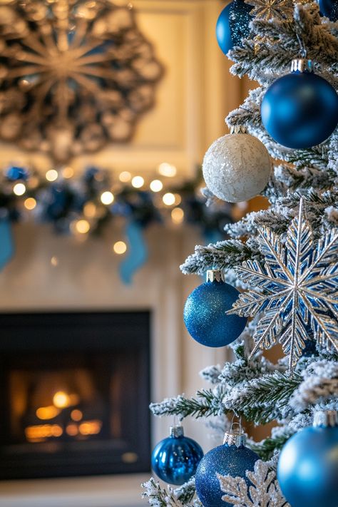 Close-up of a blue and white Christmas tree with snowflakes and ornaments, set against a beautifully decorated winter fireplace. Cozy Christmas Bedroom Aesthetic, Blue Christmas Theme, Blue Christmas Decor Ideas, Mantle Christmas Decor Ideas, Blue Flower Garland, Snowflake Pillows, Blue Christmas Tree Decorations, White Trees, Blue Christmas Decor