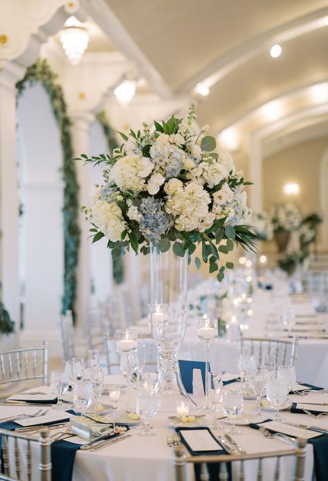 Tall white and light blue floral arrangement centerpiece atop a clear glass vase with floating candles in stemware to surround. PC Caroline Morris Photography https://carolinemorrisphotography.com/ Tall Vase Centerpieces, Blue Centerpieces, Clear Glass Vase, Cricket Club, Clear Glass Vases, Vase Centerpieces, Tall Vases, Floating Candles, French Blue