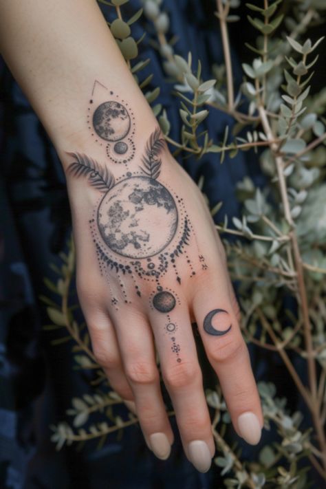 Intricate moon phase tattoo with celestial patterns on a hand surrounded by foliage. Planet Hand Tattoo, Celestial Hand Tattoos For Women, Viking Hand Tattoos For Women, Hand Tattoos For Women Unique Ideas, Hand Tattoos Moon, Space Hand Tattoo, Witchy Finger Tats, Unique Finger Tattoos For Women, Celestial Hand Tattoo