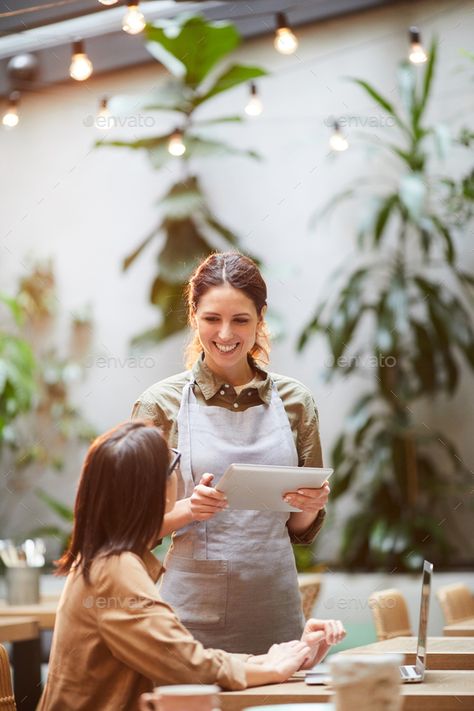 Making order in coffee shop by seventyfourimages. Cheerful pretty waitress in apron using tablet while talking to guest, businesswoman sitting at table with laptop and... #AD #Cheerful, #seventyfourimages, #waitress, #pretty Waitress Photography, Customer Photography, Profile Photography, Waitress Apron, Female Chef, Waves Photography, Thanks A Latte, How To Order Coffee, How To Make Coffee