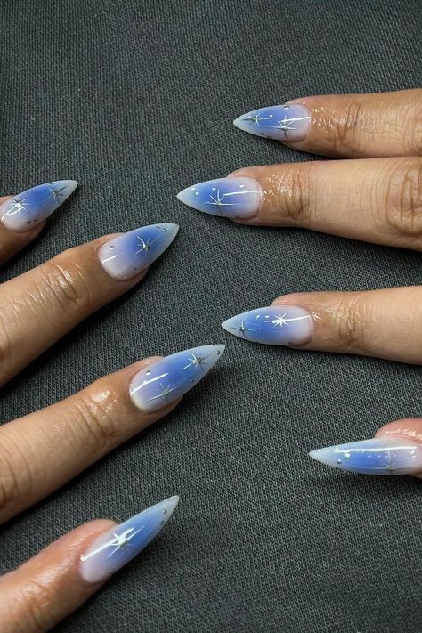 These stiletto nails showcase a dreamy gradient from periwinkle to blush, reminiscent of twilight skies. Each nail is dotted with delicate white star designs that add a touch of magic. Perfect for those who love a bit of whimsy in their look. ✨  // Photo Credit: Instagram @nailsbyxojess Pretty Blue Nails, Dreamy Gradient, Aura Azul, White Stiletto Nails, Pink Stiletto Nails, Stiletto Shaped Nails, Red Stiletto Nails, Sophisticated Manicure, Medium Stiletto