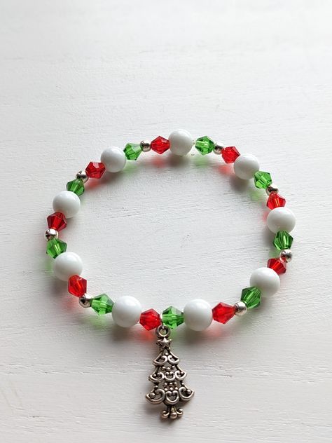 Handmade stretchy beaded Christmas charm bracelets. Perfect to add a little cheer to your holiday outfit. Makes a great gift. Comes with either a red or green assorted mesh gift bag. These ready to ship handmade bracelets are sized at 7 1/2 inches. The perfect gift How to order: Choose your bracelet type from drop down menu. The photo will auto to the type of bracelet. Choose the type you would like to order and check out. How to Measure Your Wrist:  take a flat tape measure and measure around your wrist in inches, where you wear the bracelet. If you want the bracelet to be snug/tight excat inches. If you want it to be a little lose  size up to a half-to full inch. Christmas Stretch Bracelets Ideas, Holiday Beaded Bracelets, Christmas Beaded Jewelry, Christmas Bracelet Ideas, Christmas Beaded Bracelets, Holiday Jewelry Ideas, Beaded Decorations, Handmade Bracelets Tutorial, Bracelets Christmas