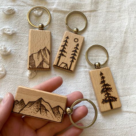 There are 4 wood rectangular keychains with woodburned designs. There is a vertical mountain, horizontal mountain, a cedar tree and a camping themed one. Keychain Wood Ideas, Woodburning Keychain Ideas, Wood Burned Keychain Ideas, Wood Burning Keychain, Woodburn Keychain, Wood Burned Keychain, Wood Burning Keychain Ideas, Wooden Keychain Ideas, Camping Keychain