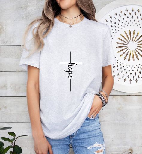 🙏 "Hope Cross" 🙏Let your faith be your anchor, and let hope be your guide. Our T-shirt combines the timeless symbol of the cross with the powerful message of hope. 🌟Wear it proudly and inspire others to find hope in every moment. ✨#FaithHopeLove #ChristianFashion #HopeInChrist #WearYourFaith #InspireHope #BelieveInMiracles Inspirational Bible Verse, Church Shirt, Christian Tshirt, Jesus Faith, Timeless Symbol, Christian Fashion, Religious Shirt, Catholic Quotes, Hope Symbol