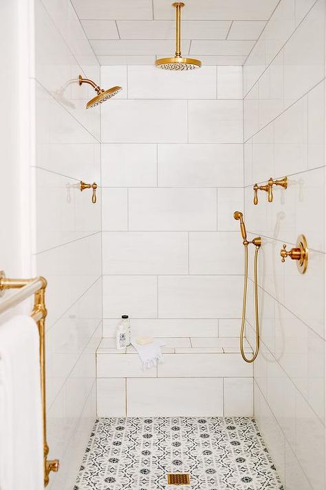 Multiple brushed gold shower heads are mounted to white staggered shower surround tiles, as a brushed gold rain shower head is fixed over white and gray mosaic floor tiles ending at a white tiled bench. Small Bathroom Floor Tile Ideas, Small Bathroom Floor Tile, Bathroom Flooring Tile, Small Bathroom Flooring, White Shower Tile, Budget Small Bathroom, Multiple Shower Heads, White Tile Shower, Shower Floor Tile