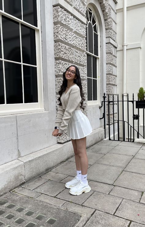 Tennis Skirt Cardigan Outfit, Cardigan And Tennis Skirt, Beige Tennis Skirt Outfit, White Tennis Skirt Outfit Winter, Beige Skirt Outfit Winter, Tenis Skirt Outfits, Tennis Skirt Outfit Winter, Cardigan With Skirt, White Pleated Skirt Outfit