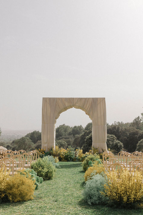 A serene ceremony setup in nature 🌿 This minimalist, elegant archway surrounded by lush greenery and soft yellow blooms creates the perfect backdrop for a romantic outdoor wedding. With simple wooden chairs and an open-air ambiance, it’s an idyllic spot to say 'I do.' 🌞 #OutdoorWedding #WeddingArch #NatureInspired #MinimalistWedding #CeremonyDecor Wood Aisle Wedding, No Arch Wedding Ceremony, Minimalist Wedding Aisle, Indoor Wedding Ceremony Backdrop, Meadow Wedding Ceremony, Simple Wooden Chairs, Outdoor Field Wedding, Outdoor Ceremony Backdrop, Modern Ceremony Backdrop