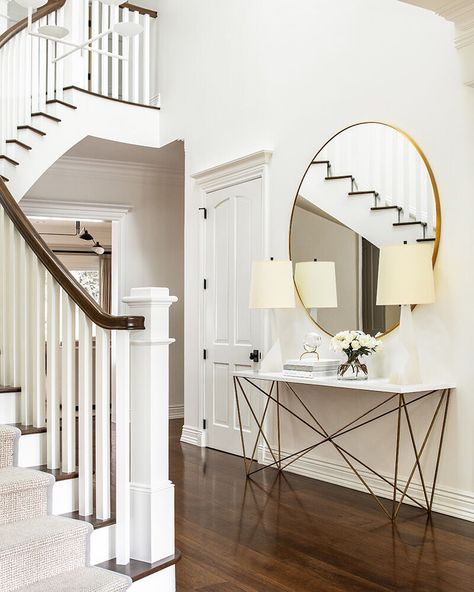 Entryway with a curved staircase, walnut floors, and a round mirror, blending modern design with classic charm. Concrete Fireplace Surround, Entryway Styling, Functional Entryway, San Francisco Interiors, Entryway Style, Elegant Entryway, Statement Lamp, Concrete Fireplace, Walnut Floors