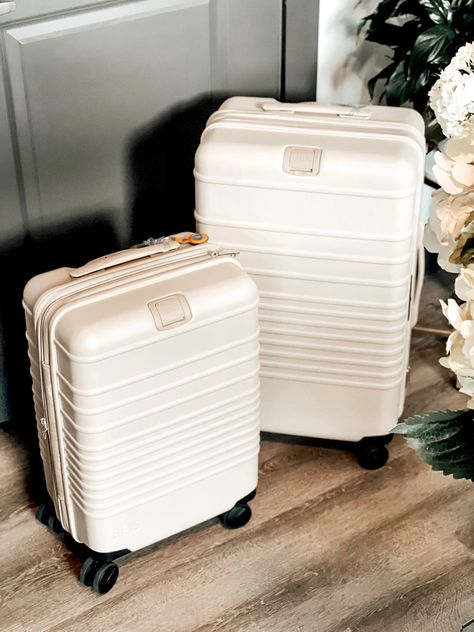 Set of beige rolling spinner luggage and apple AirTag charm. White Luggage Set, Small Luggage Suitcases, White Suitcase Aesthetic, Cute Carry On Luggage, Cute Luggage Sets, Bali Essentials, Teen Luggage, White Suitcase, Cute Suitcase