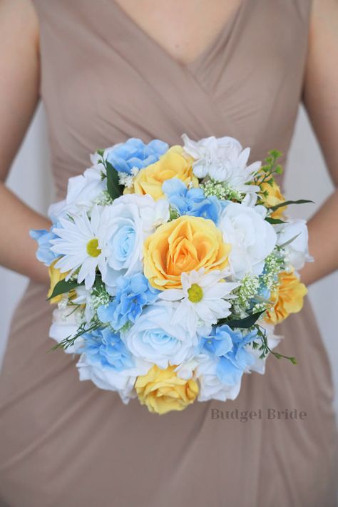 This lovely assortment of light blue and yellow is bound to turn heads on your wedding day. This lovely cascading brides’ bouquet from the is an absolutely breathtaking arrangement for any bride to be, in any season. White shasta daisies and mixed greenery complete the look and add a delicate realism to this beautiful bouquet. This bouquet is 10” wide, 18” long, and is crafted by our in-house florists without using a foam base to anchor the flowers to the bouquet. Instead, we wire our bouquets b Dusty Blue And Yellow Bouquet, Wedding Colors Blue And Yellow, Blue And Yellow Wedding Bouquet, Blue And Yellow Wedding Flowers, Yellow And Blue Bouquet, Light Blue And Yellow Wedding, Blue And Yellow Bouquet, White Wedding Flower Arrangements, Yellow And Blue Wedding