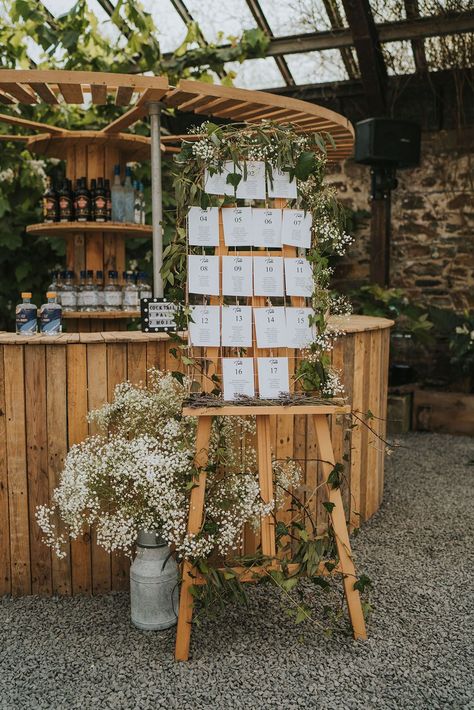 Foliage and gypsophila decorating the wooden seating chart and table plan sign next to the bar Seating Chart Wedding Clothespin, Unique Seating Chart Wedding Boho, Rustic Wedding Table Plan, Barn Wedding Seating Chart, Whimsical Wedding Seating Chart, Wooden Seating Chart Wedding, Woolshed Weddings, Table Chart Wedding, Seating Plan Wedding Rustic