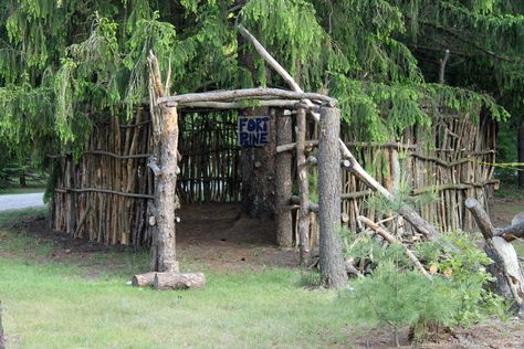 Fort Pine is a hut style fort at the base of a huge pine tree. Similar to something seen on Gilligan's Island, trees trunks and limbs create the surrounding walls and entrance. Forts In The Woods, Wood Forts In The Woods, Outdoor Fort Ideas, Tree House Village, How To Build A Fort Outside, Forest Fort, Fort In The Woods Diy, Simple Tree Fort, Diy Stick Fort Outdoor