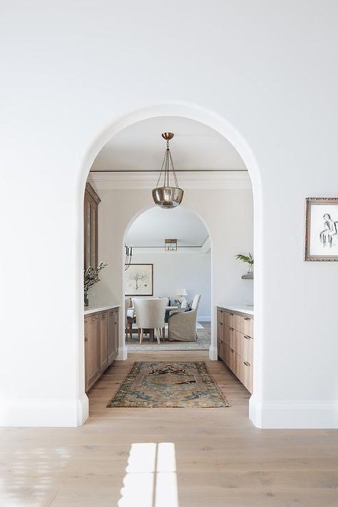 An arch doorway leads to galley style butler's pantry boasting a tan and gray vintage rug placed on a light gray wash wooden floor. Modern Arched Doorways Interior, Doorway To Archway, Archway Dining Room, Arches In Homes, Arched Doorways Interior, Modern European Home Interior Design, Interior Arches, Arched Interior, Modern English Country