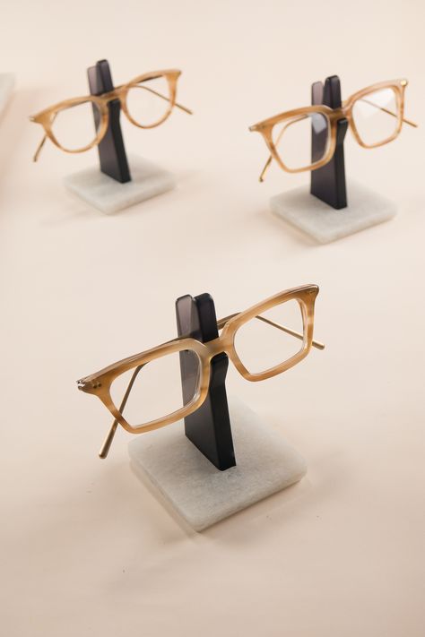 An understated glasses holder to store your spectacles. On your work desk in the office or your bedside table, this minimal Spectacles Holder is the perfect place to hang your eyeglasses. Constructed from recycled plastic bottles, the sturdy base-plate keeps your frame nice and high, away from dust and scratches. This semi-translucent edition is made from a transparent grey upright, with smoothly polished edges and a silky satin finish. Wooden Glasses Holder, Eyeglass Holder Stand, Eyewear Store Design, Eyewear Display, Personalised Glasses, Furniture Details Design, Boutique Decor, Glasses Holder, Glass Holder