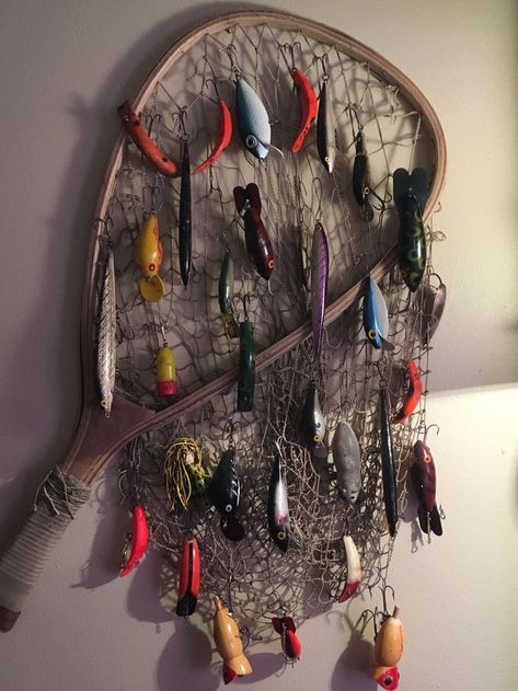 Antique fishing lures displayed on vintage net Fishing Room Decor, Lure Display, Fishing Bedroom, Fishing Lures Display, Minnow Trap, Fishing Cabin Decor, Old Fishing Lures, Fish Bathroom, Antique Fishing Lures